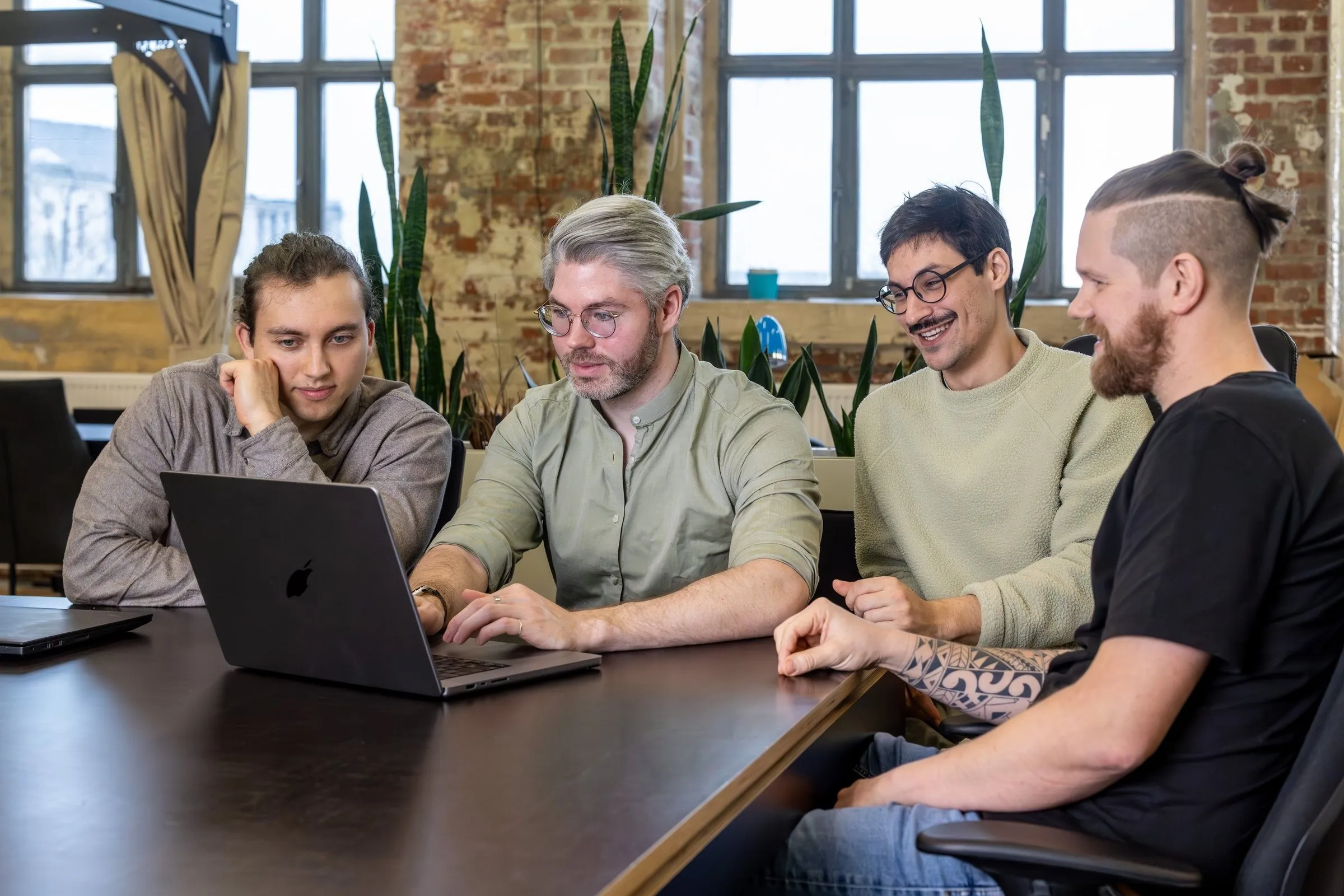 Four colleagues looking at a laptop together