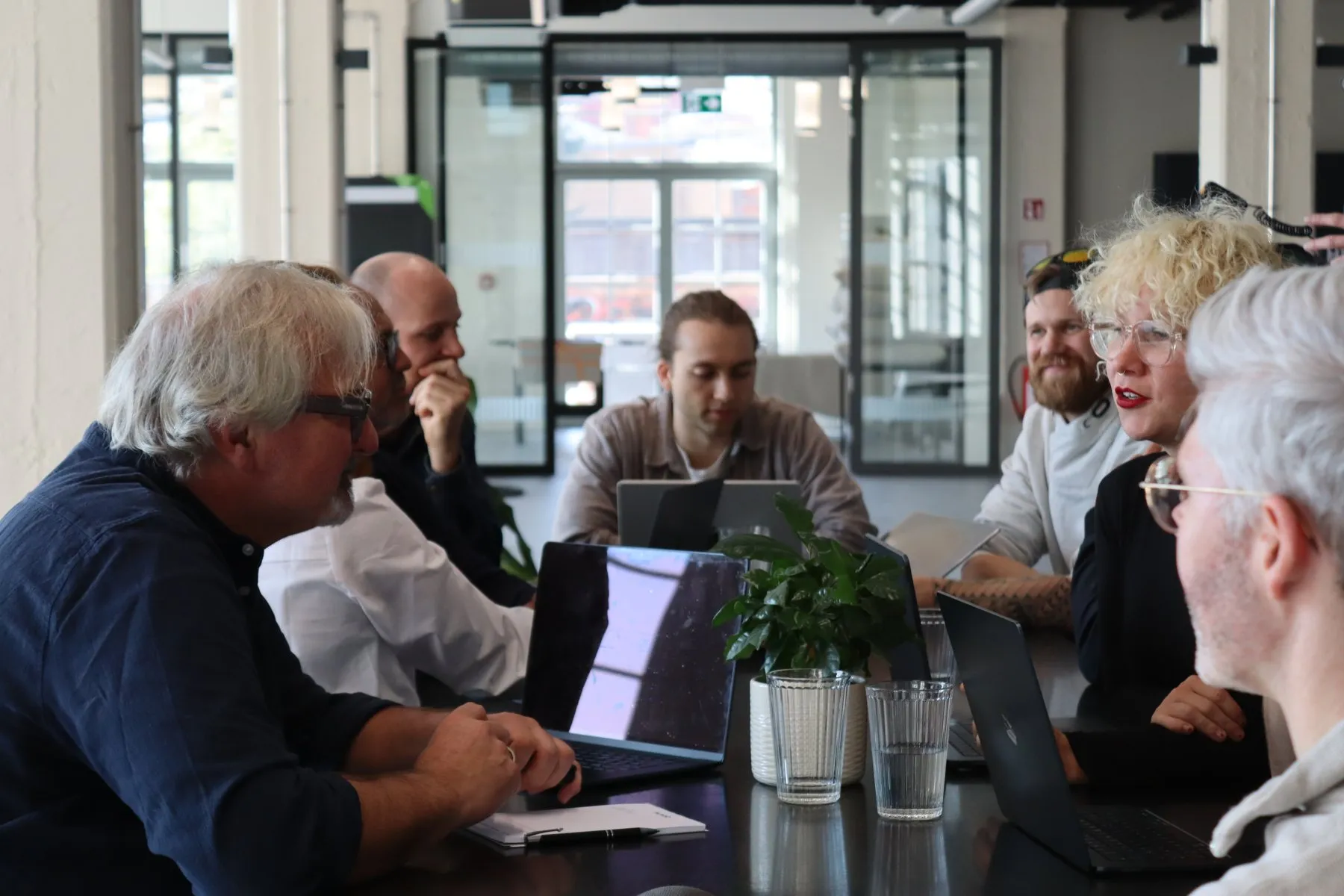 Team im Training am großen Tisch mit Laptops